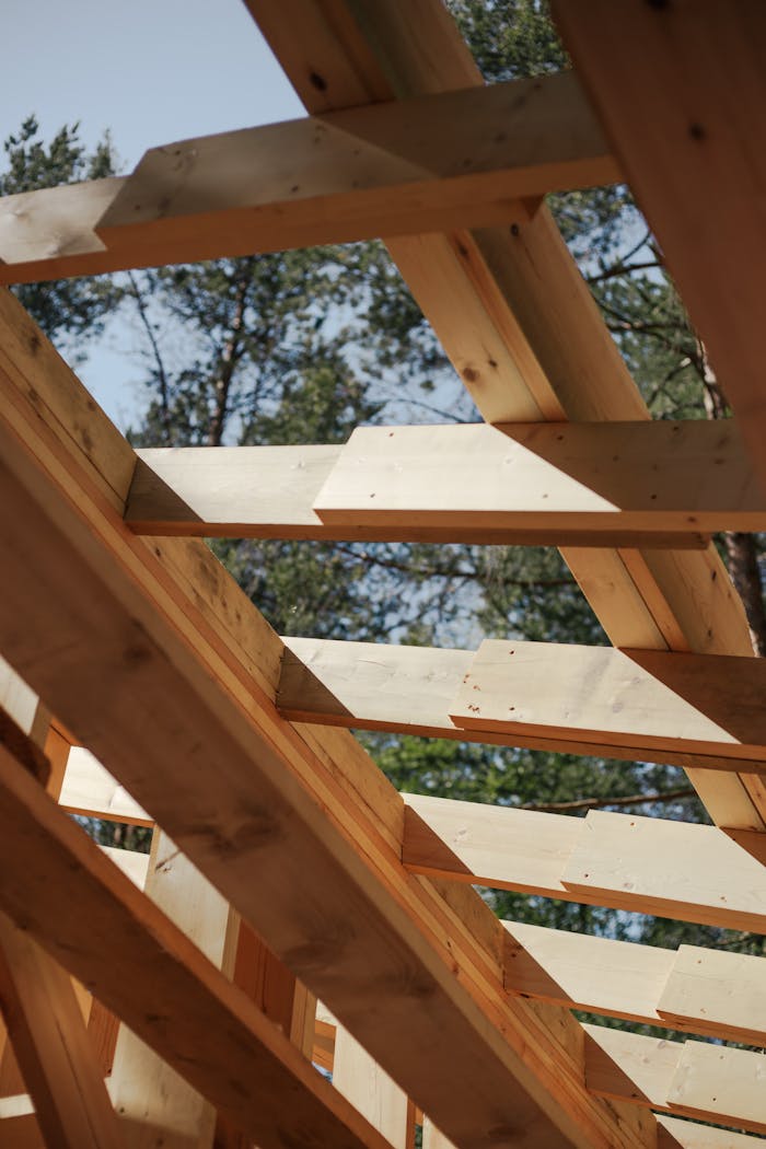 Close-up view of wooden beams forming a house roof structure against a sky background.